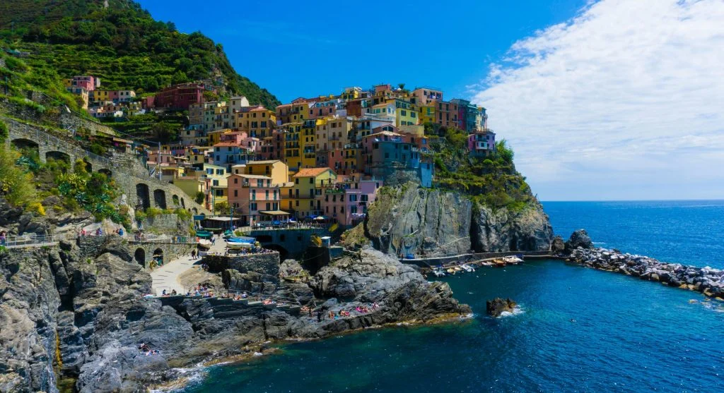 Travelers walking along a cliffside path in a picturesque coastal village