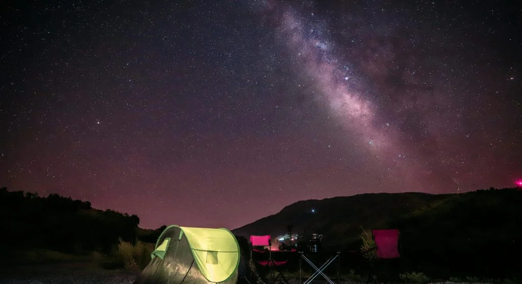 People stargazing at a luxury outdoor campsite with telescopes and comfortable seating