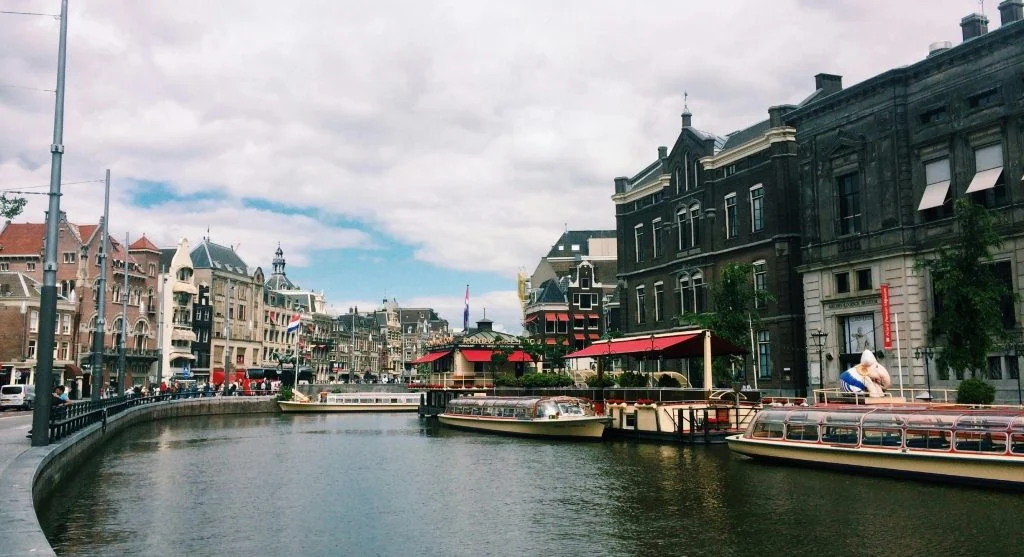 Scenic view of Amsterdam canals with luxury boats and historic buildings