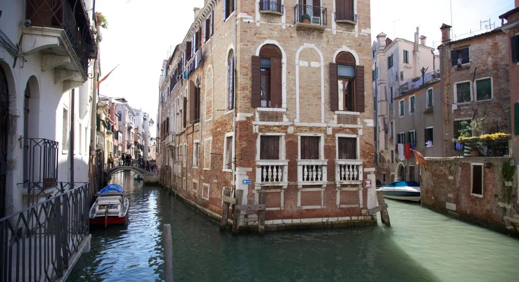 Boutique hotels along a serene canal with boats and lush greenery