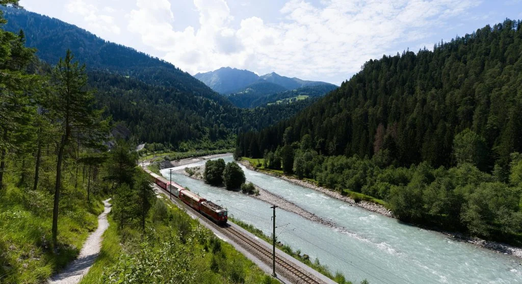 Scenic train tracks running along the edge of a serene Alpine lake