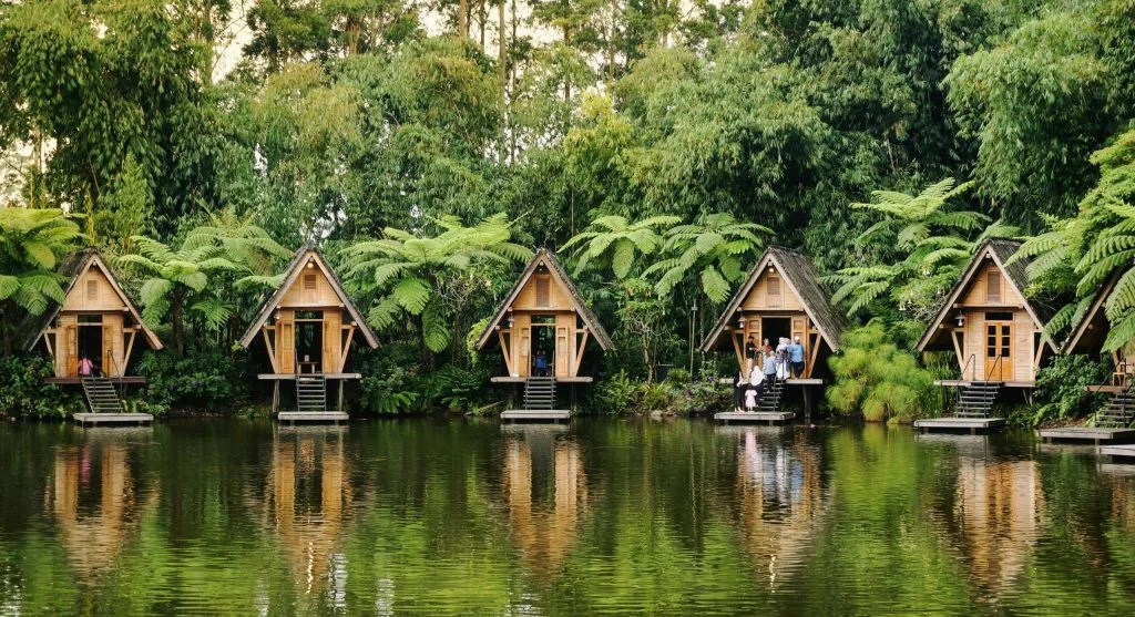 Peaceful waterfront scenery with floating eco lodges surrounded by lush greenery