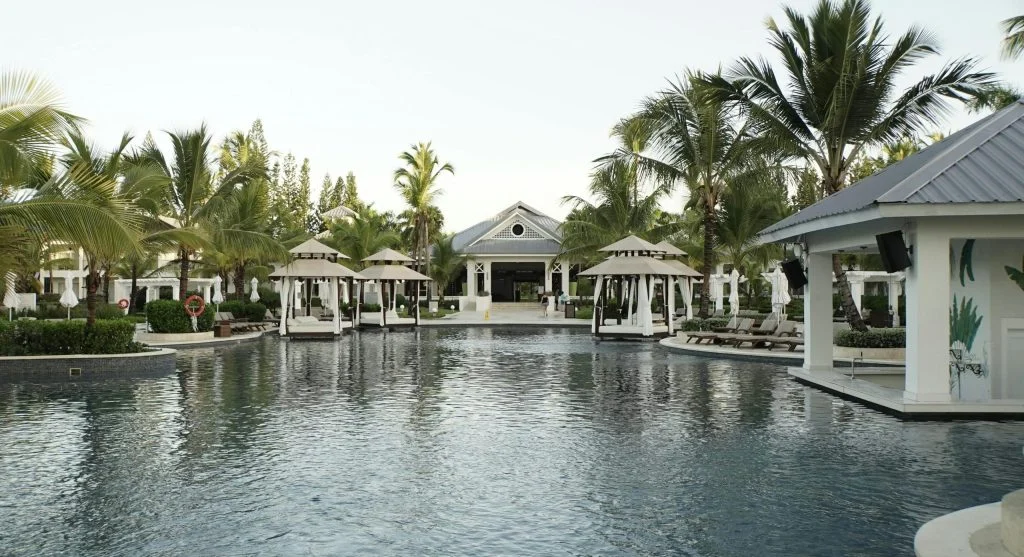 Serene waterfall surrounded by lush greenery and a wellness retreat in the background