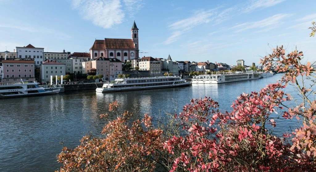 European river cruise ship sailing through a canal lined with autumn foliage