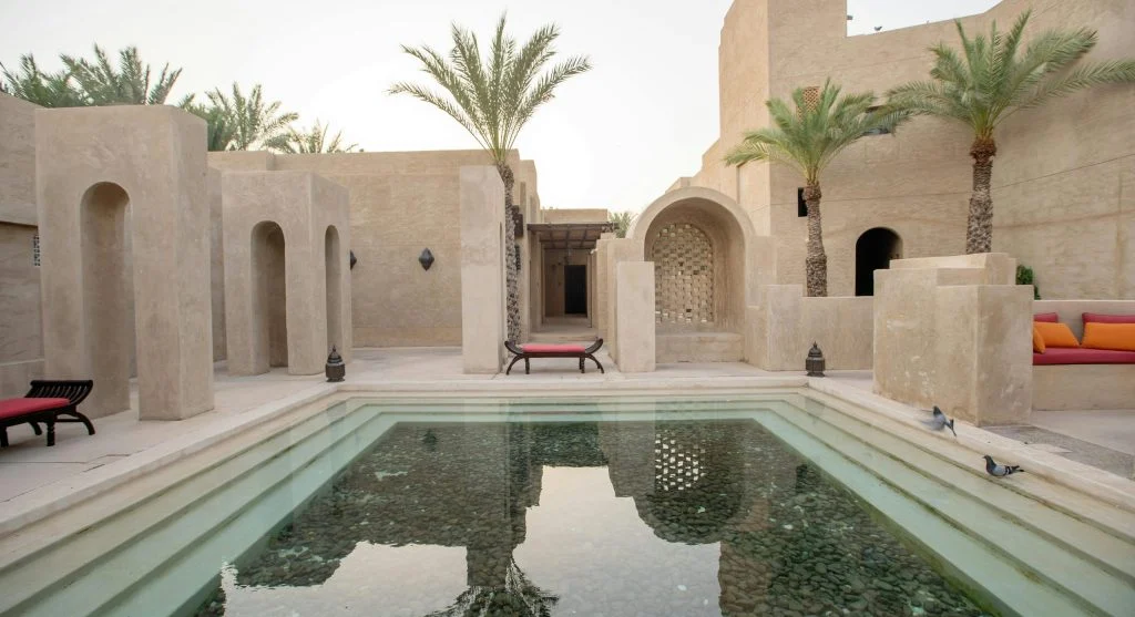 Palm trees surrounding a tranquil desert oasis with a luxurious resort in the background
